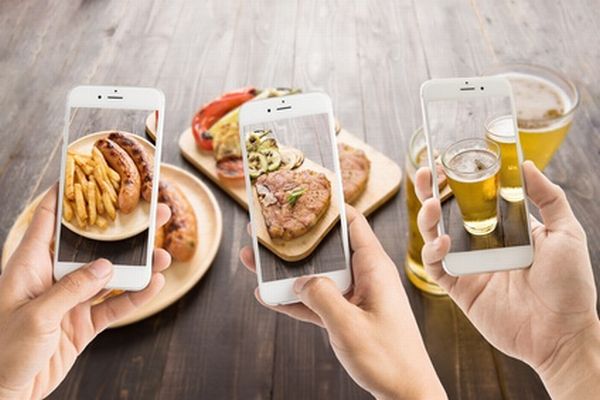friends using smartphones to take photos of sausage and pork cho