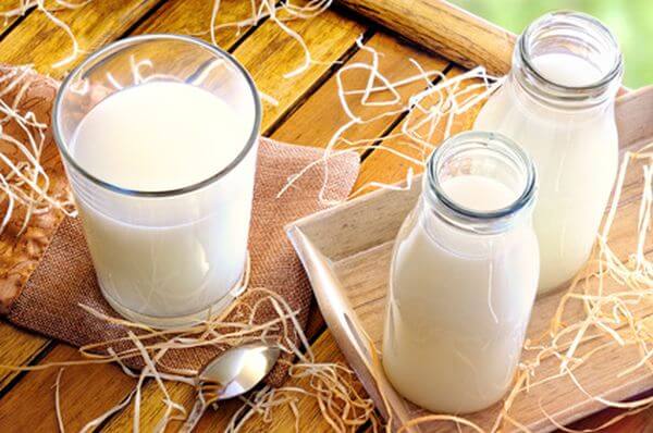 Glass of milk on a table on the field with two bottles of milk top view