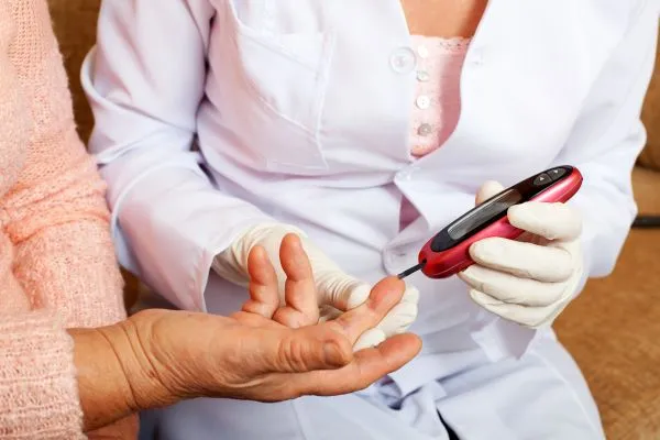 Nurse takes test for sugar in blood of elderly woman at home.