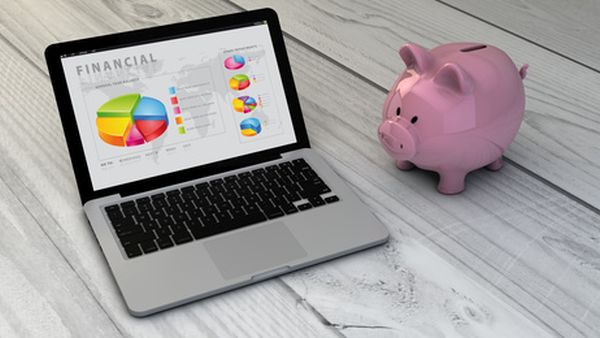 finances concept: piggybank and finances laptop over wooden desk. All screen graphics are made up