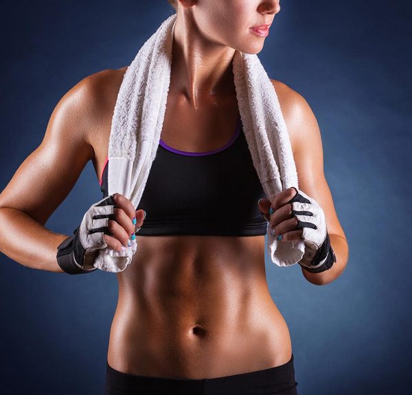 Young sports woman after workout with towel on his shoulders on a dark background