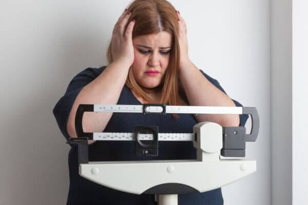 worried woman on a medical weight scale
