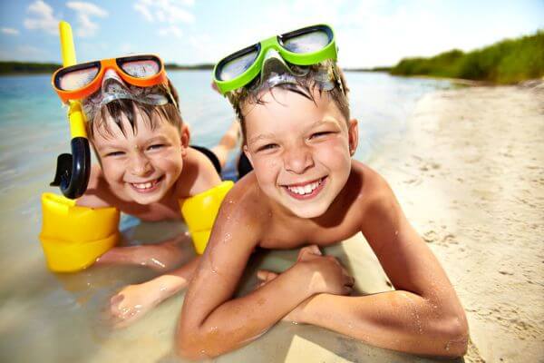 Photo of happy siblings lying on sand on summer vacation