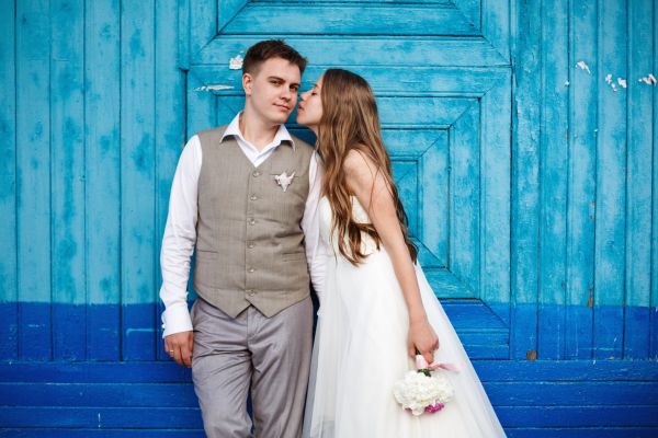 Happy stylish wedding couple having fun against blue background
