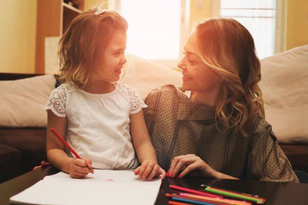Loving mother helping her daughter write a letter. Looking at each other.
