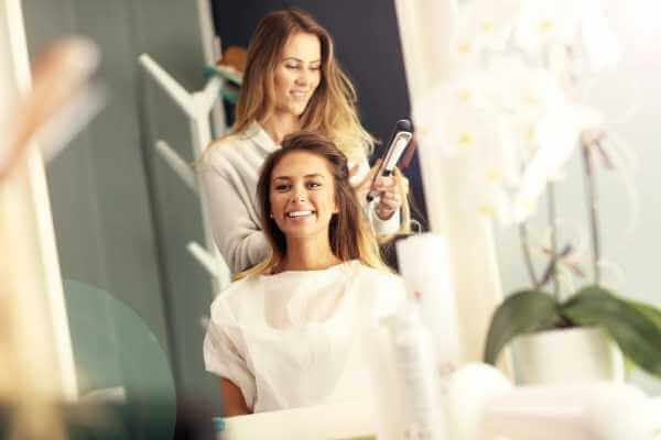 Hairdresser using hair straightener in studio