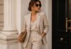 Minimalistyczna stylizacja z beżowym garniturem, białą koszulą i złotą biżuterią w stylu quiet luxury.